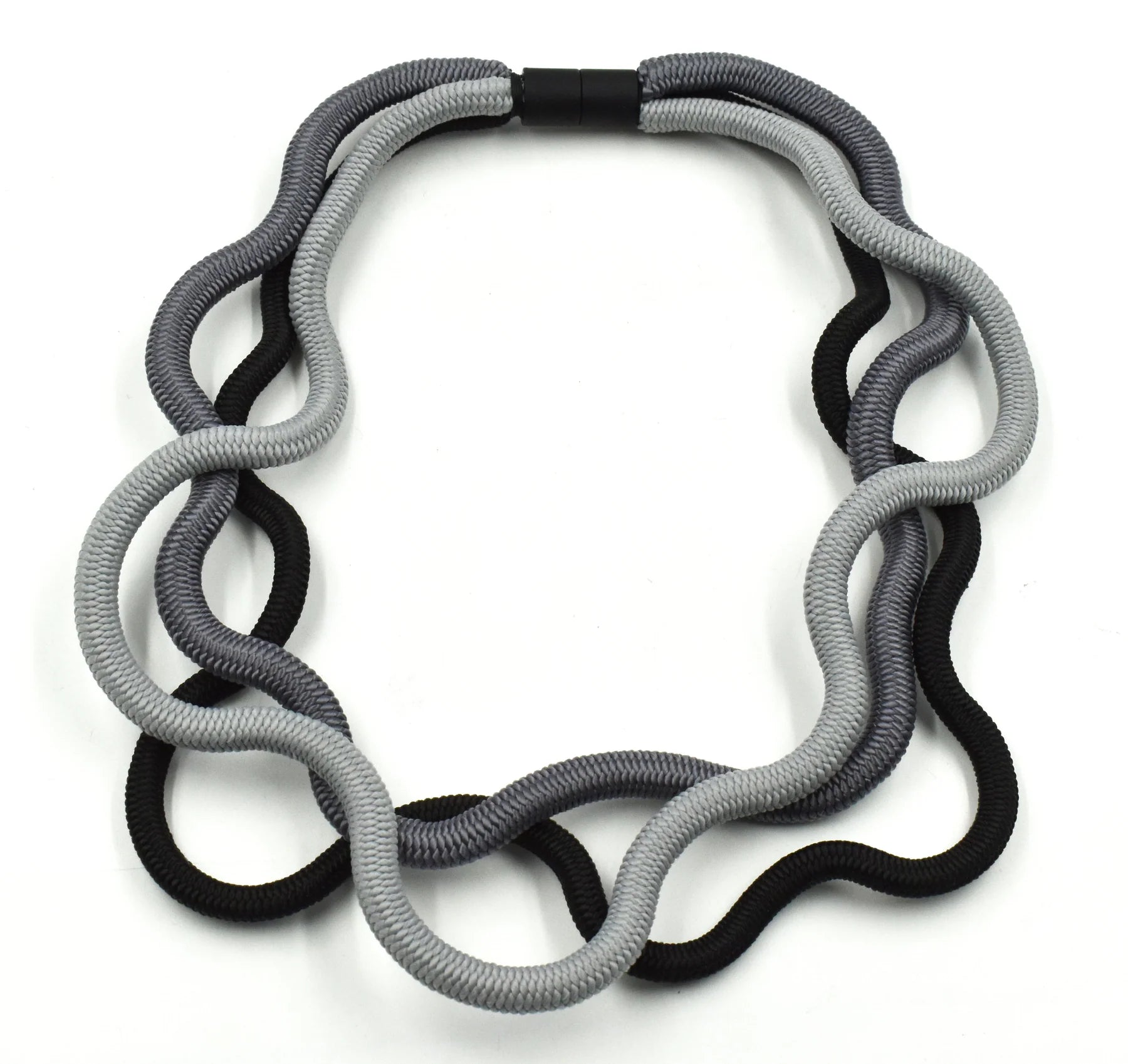 A triple cord necklace featuring three shades of grey with black clasp sat on a white background