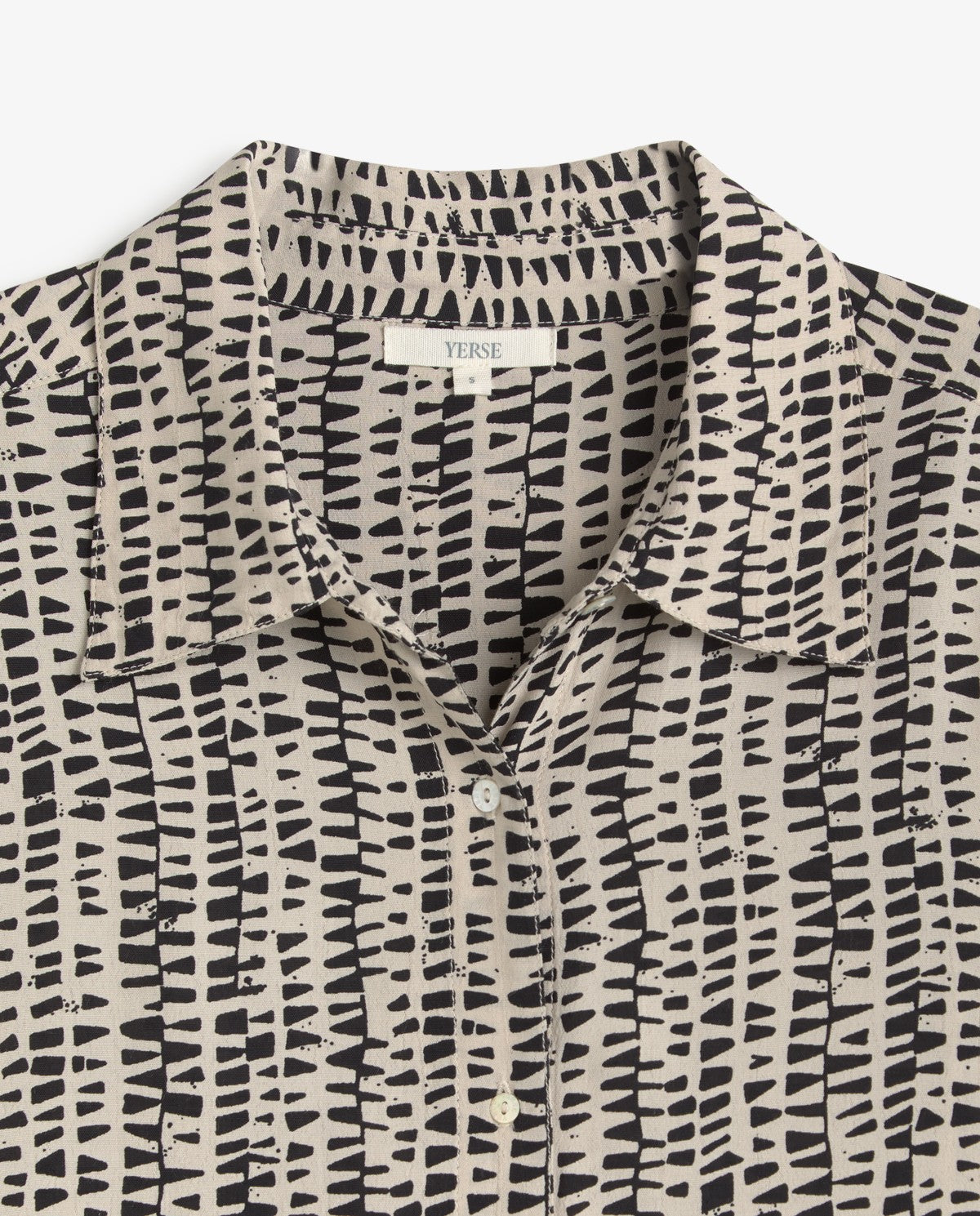 A close-up of a collared button-front shirt by Yersa, featuring a black abstract brushstroke pattern on a warm beige background.