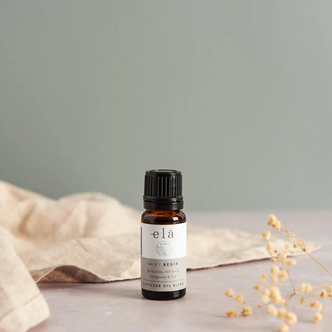 Amber glass bottle of elá No. 1 BEGIN diffuser oil blend with black cap.  Contains geranium, dill seed, bergamot, and bay.