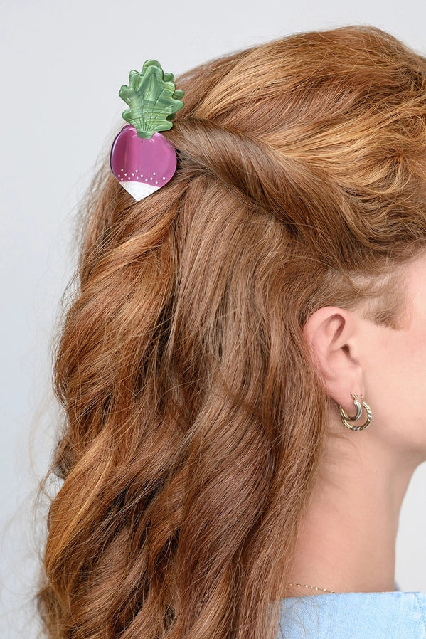 Person with wavy hair wearing a decorative hair clip on a plain background