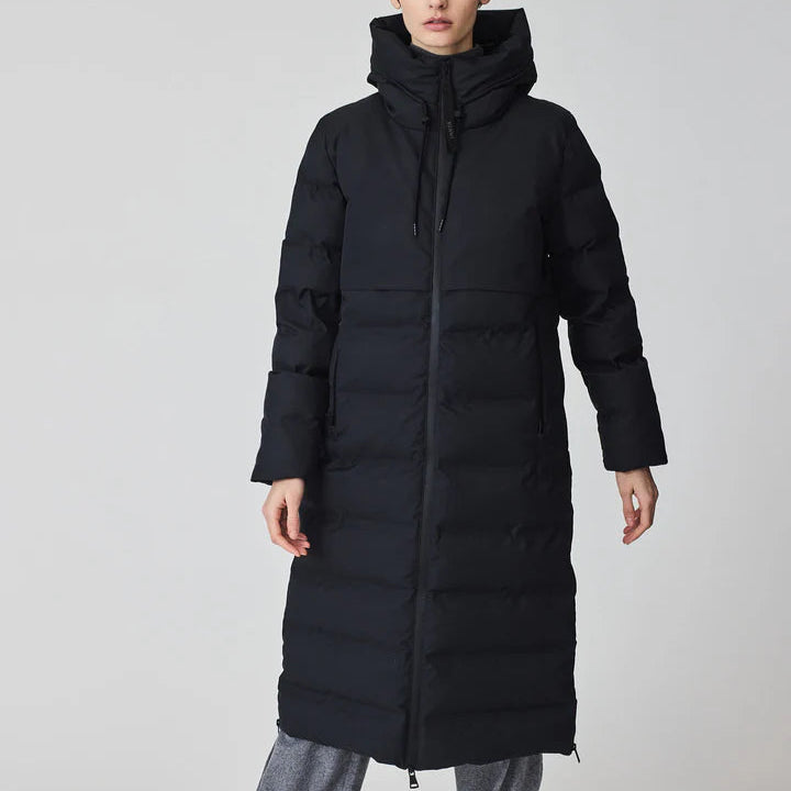 Person wearing a long black puffer coat on a plain background