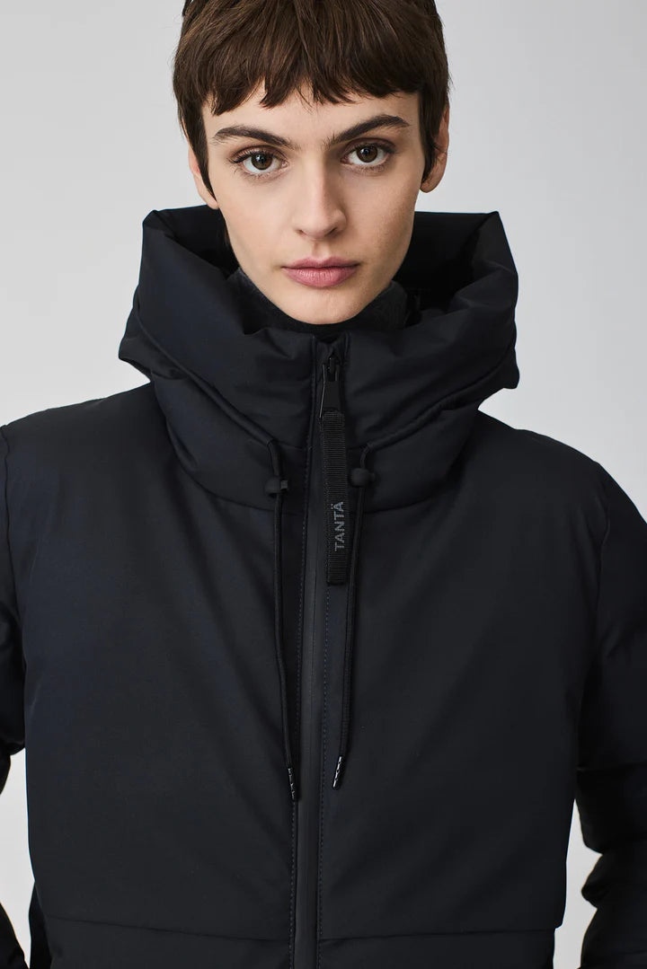 Person wearing a long black puffer coat on a light gray background
