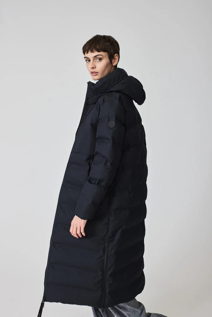 Person wearing a long black puffer coat on a light gray background