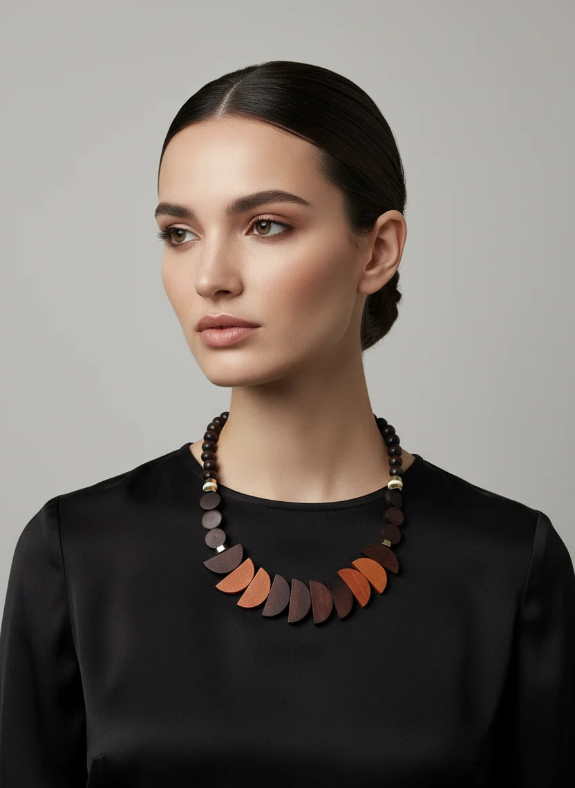 Woman wearing a black top and a colourful necklace against a grey background