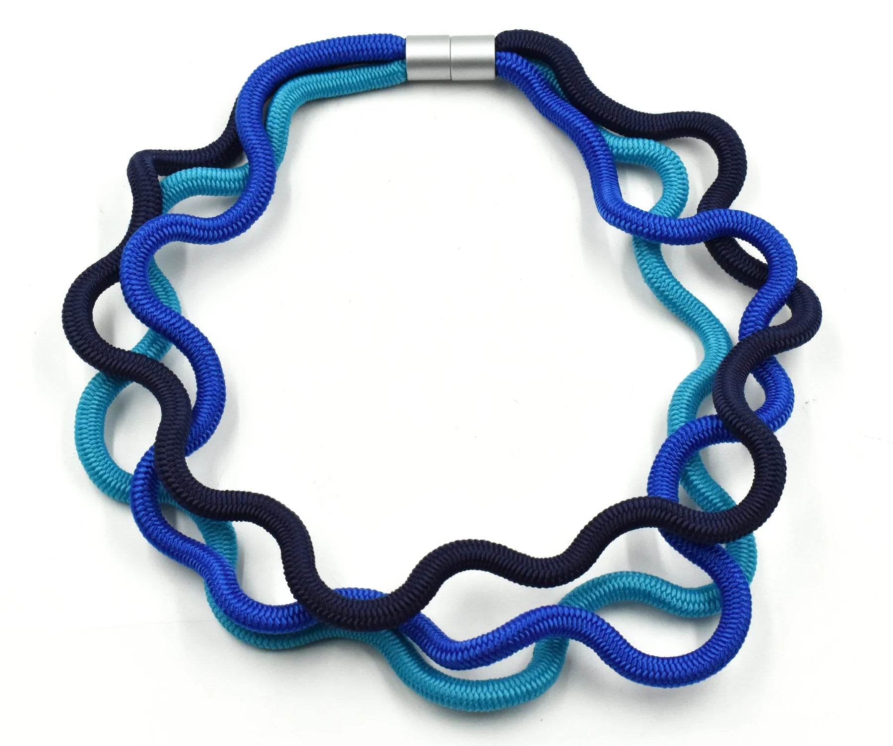 A triple cord necklace featuring three shades of blue with silver clasp sat on a white background