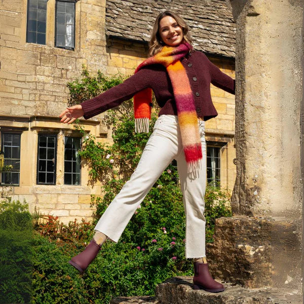 Burgundy ankle boots with a slight heel, worn by a model in a casual pose.