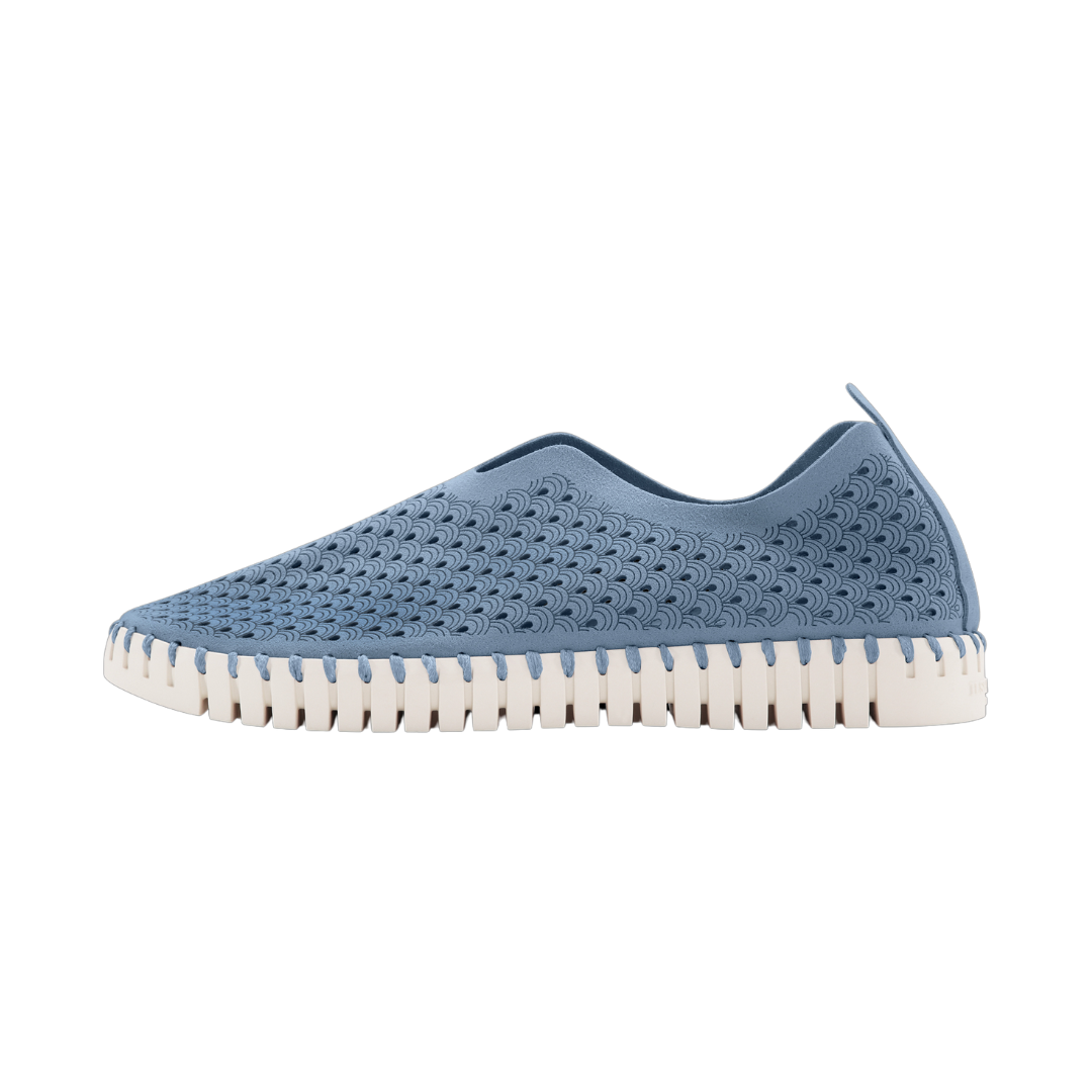 Dusty blue slip-on sneaker with textured, patterned upper and off-white, ridged sole.