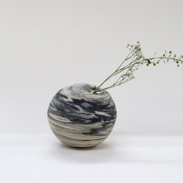 Marble-patterned vase with a branch on a white background
