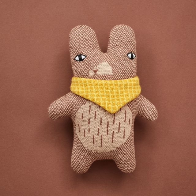 A handmade plush toy rabbit made from textured brown and beige fabric, wearing a yellow gingham bandana, set against a solid brown background.