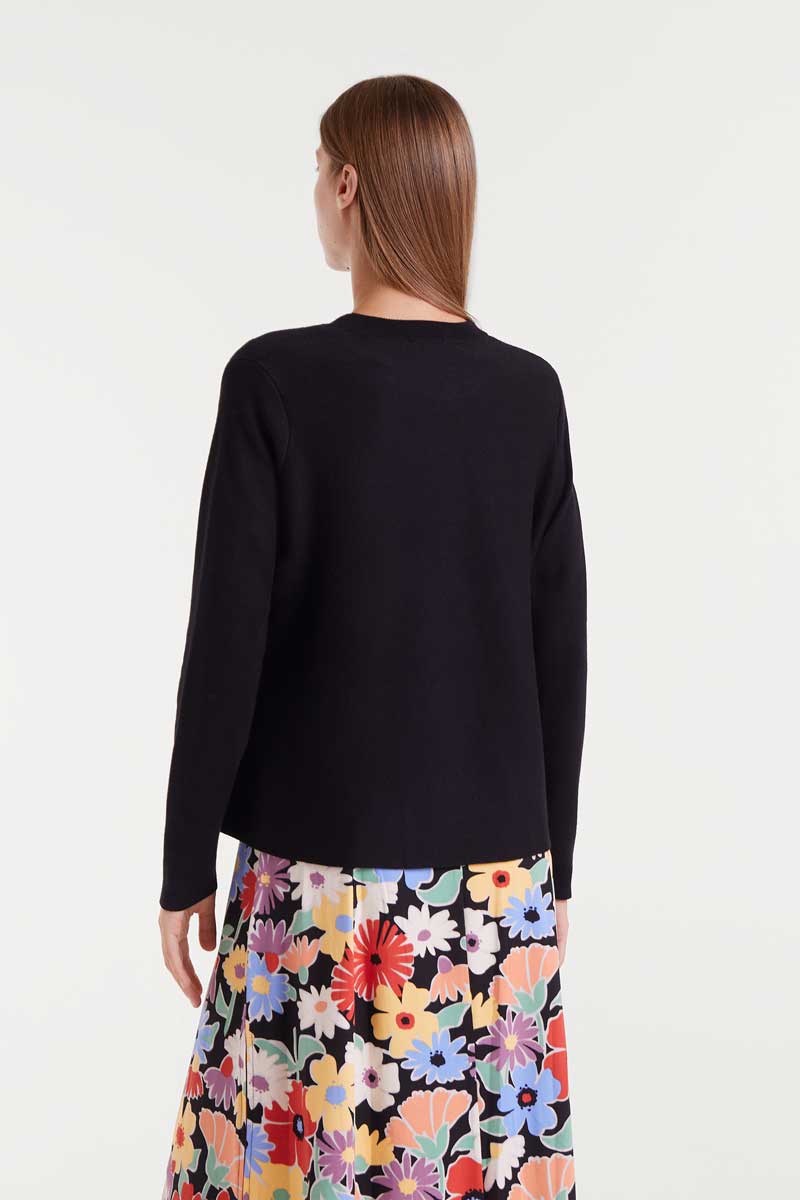 Woman wearing a black top and colorful floral skirt on a white background