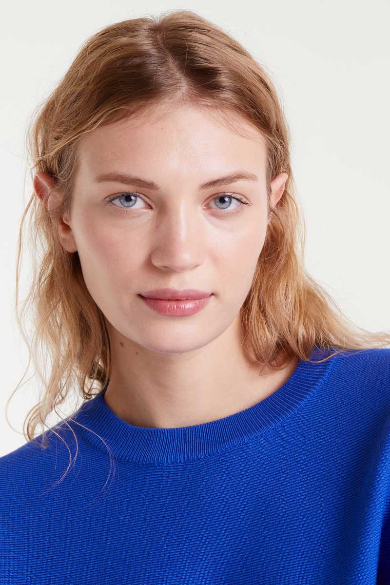 Woman wearing a blue sweater against a white background