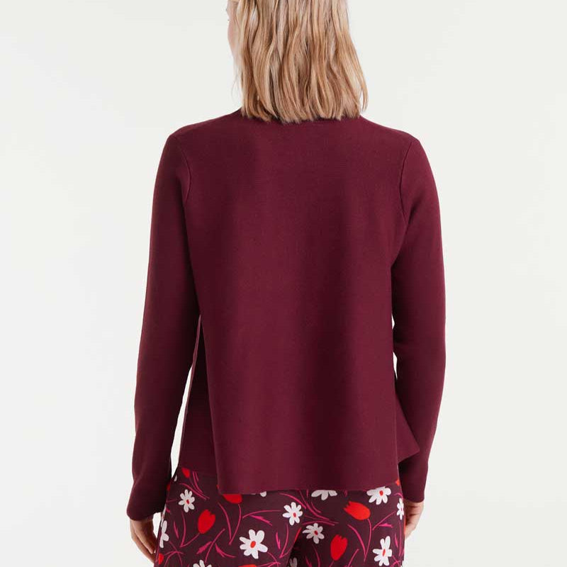 Person wearing a burgundy cardigan over floral pants on a white background