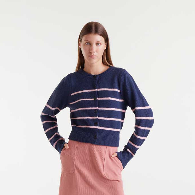 Woman wearing a navy cardigan with pink stripes on a white background
