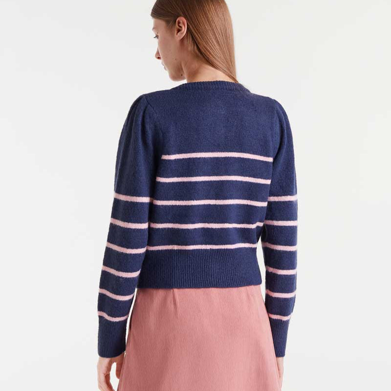 Woman wearing a navy sweater with pink stripes and a pink skirt on a white background
