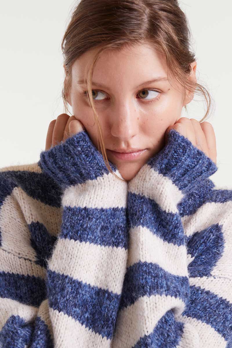 Woman wearing a blue and white striped sweater with a white background