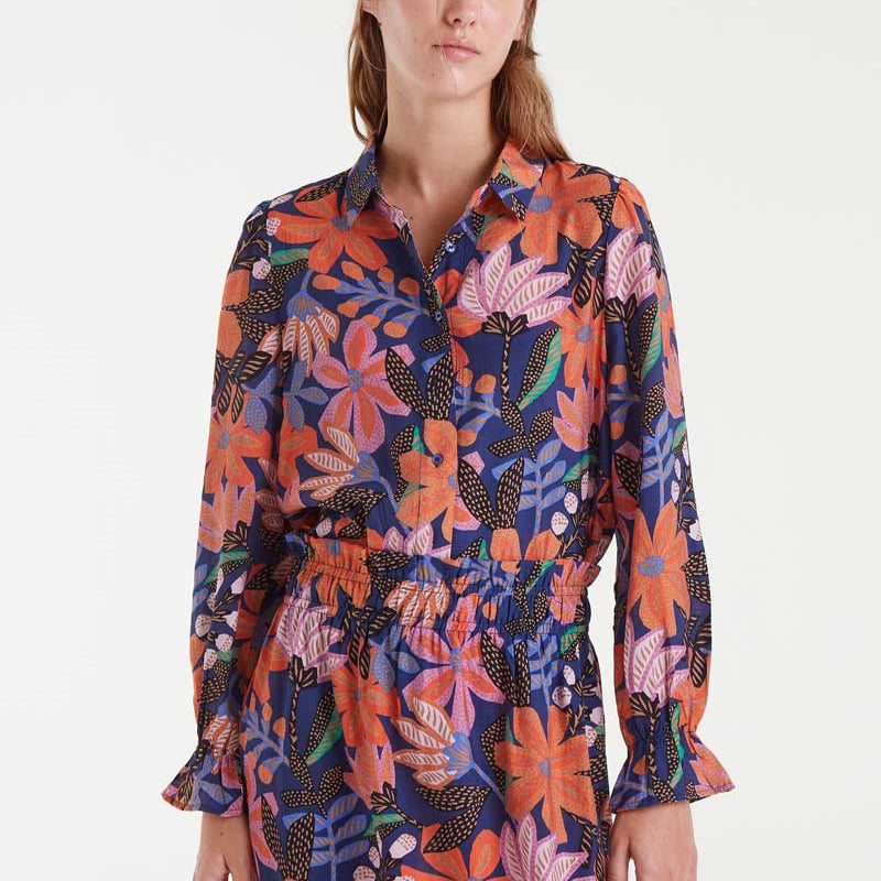 Woman wearing a colorful floral blouse and skirt on a white background
