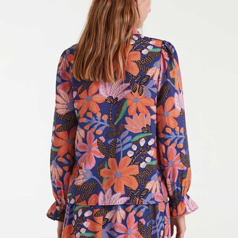 Woman wearing a colorful floral blouse and skirt on a white background