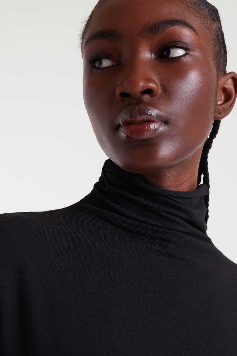 Person wearing a black turtleneck against a white background
