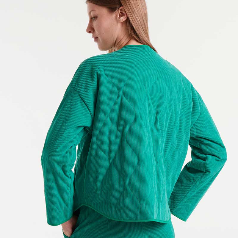 Person wearing a green quilted jacket on a white background