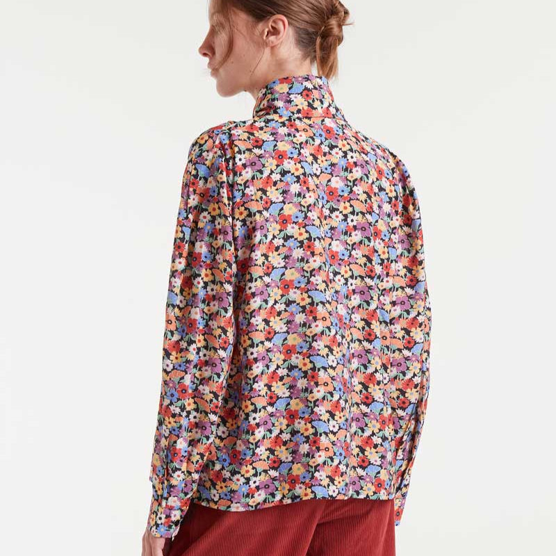 Woman wearing a colorful floral blouse on a white background