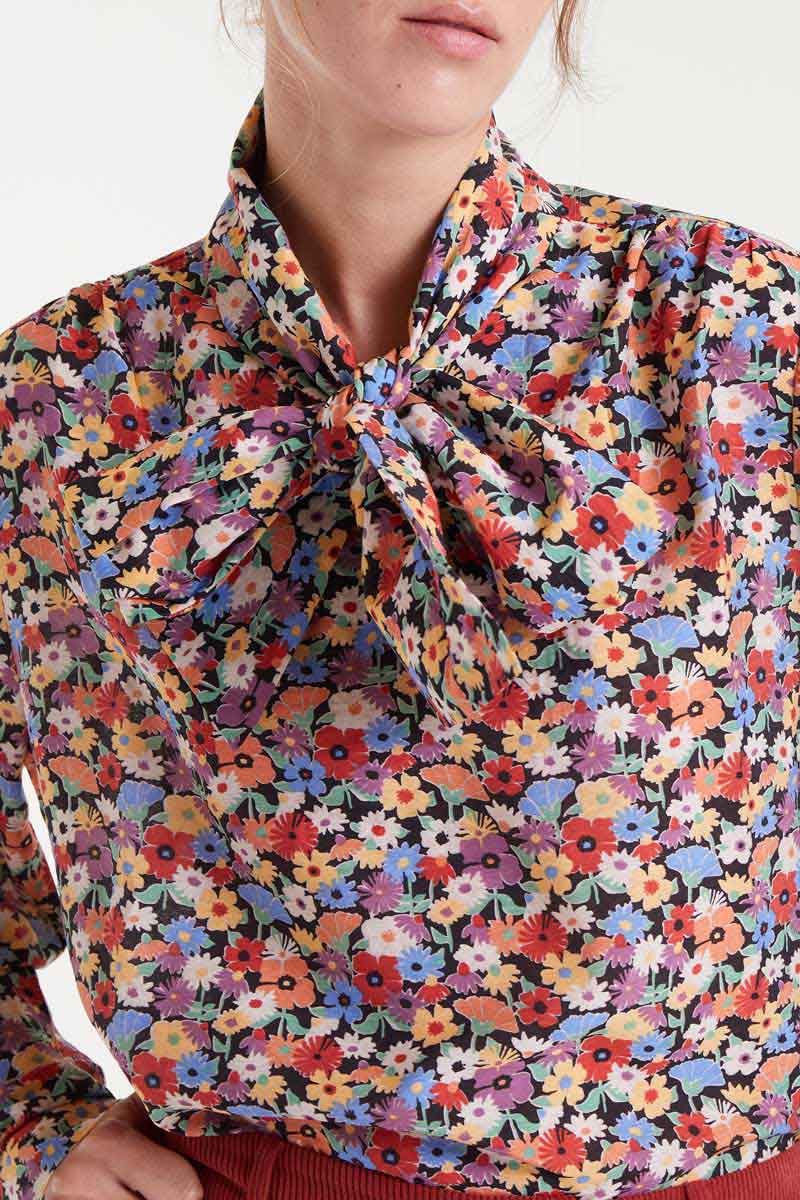 Multicolored floral blouse with a tie neckline on a white background