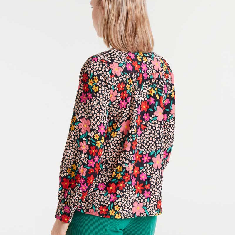 Woman wearing a colorful floral blouse on a white background