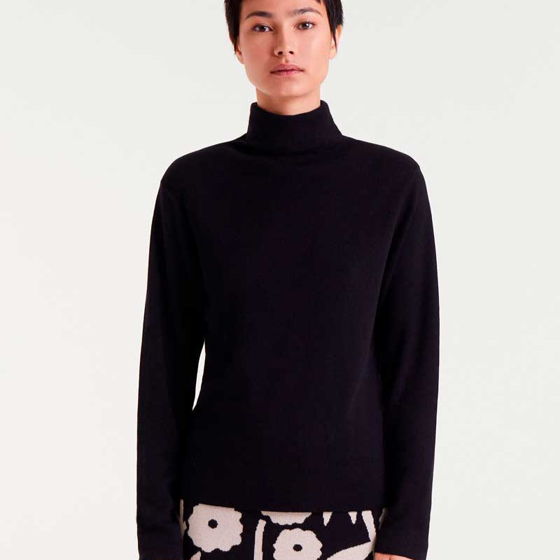 Person wearing a black turtleneck sweater with a white floral pattern on a light gray background