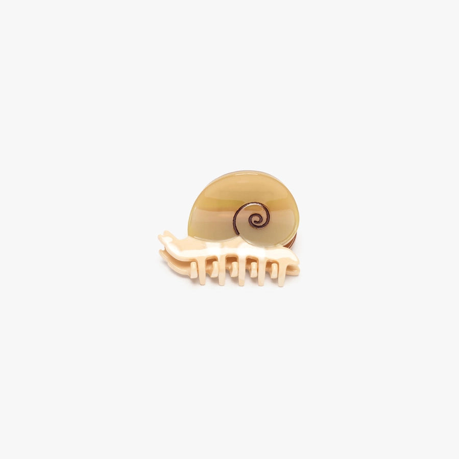 A small shell-shaped hair claw clip designed to look like a snail, featuring a glossy beige shell top and a cream-colored plastic claw base, shown on a plain light gray background.