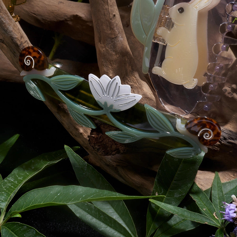 Decorative elements including a rabbit figurine, leaves, and flowers on a natural background.