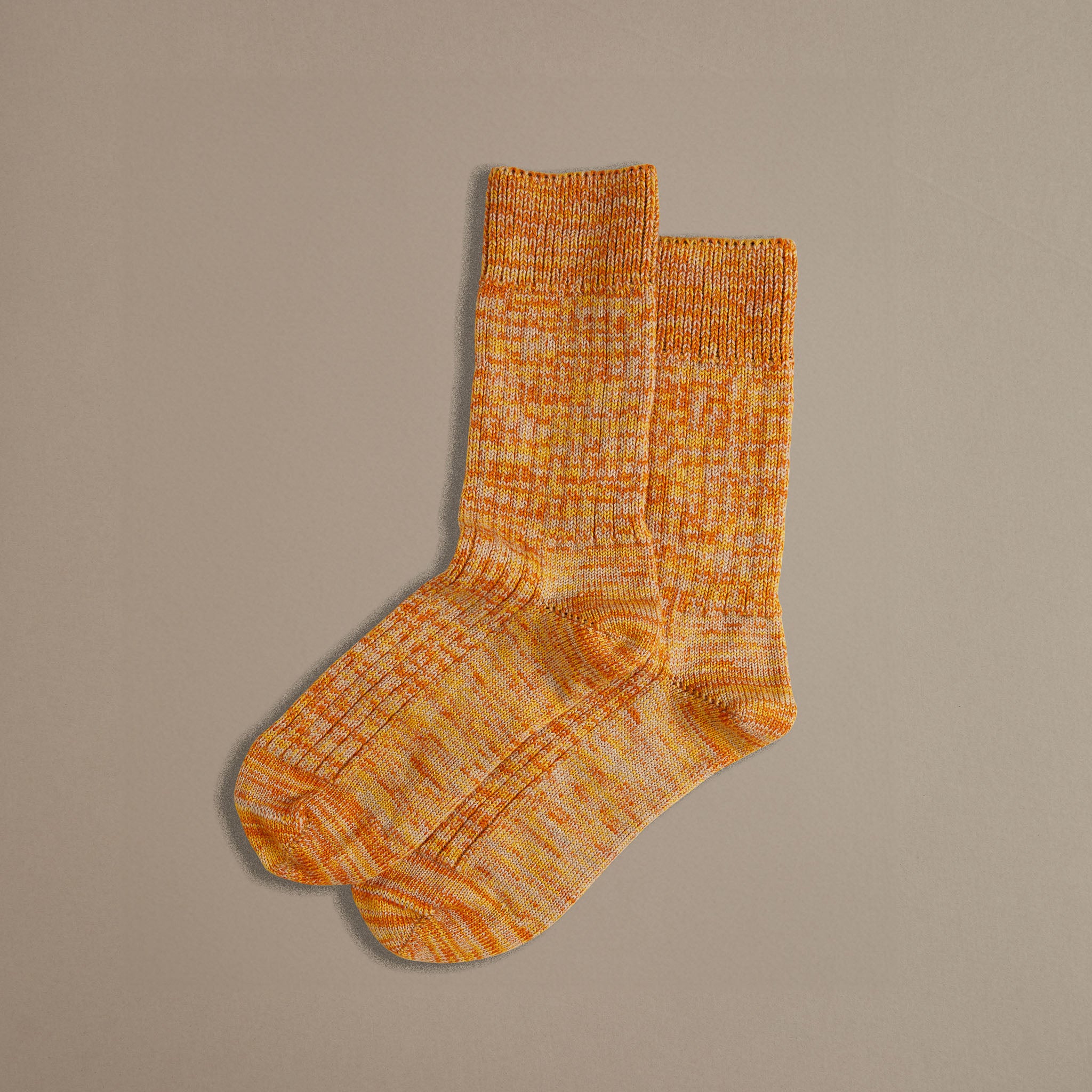 Pair of orange crew socks with a speckled, multicolored knit.