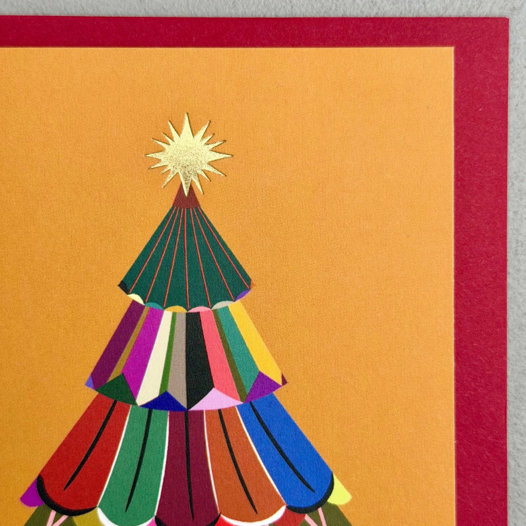 A close-up of a colorful Christmas tree illustration on a warm orange background with a red border, showing layered tree shapes in green, red, purple, yellow, blue, and pink with a gold star on top.