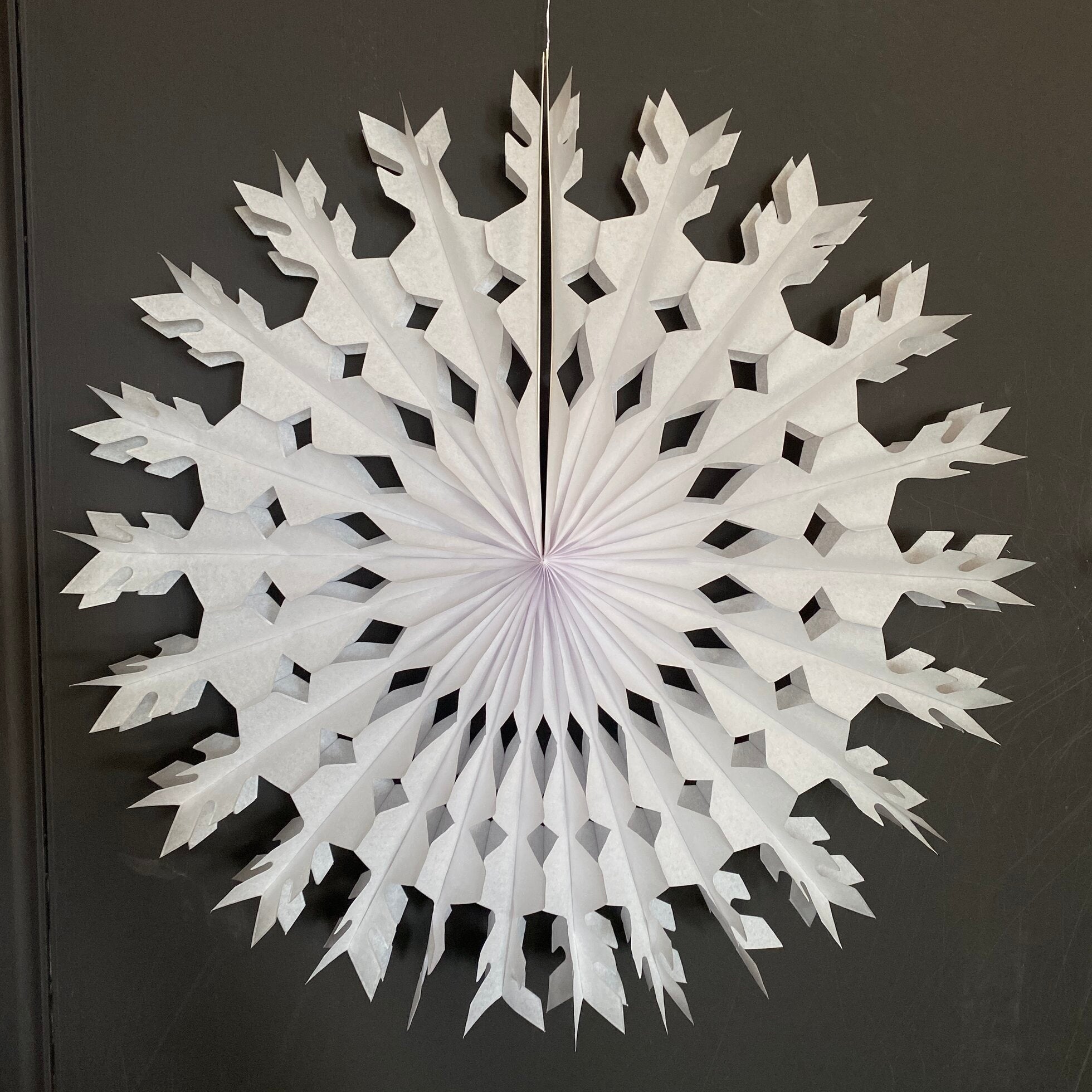 Large white paper snowflake decoration with cut-out diamond and pointed details.