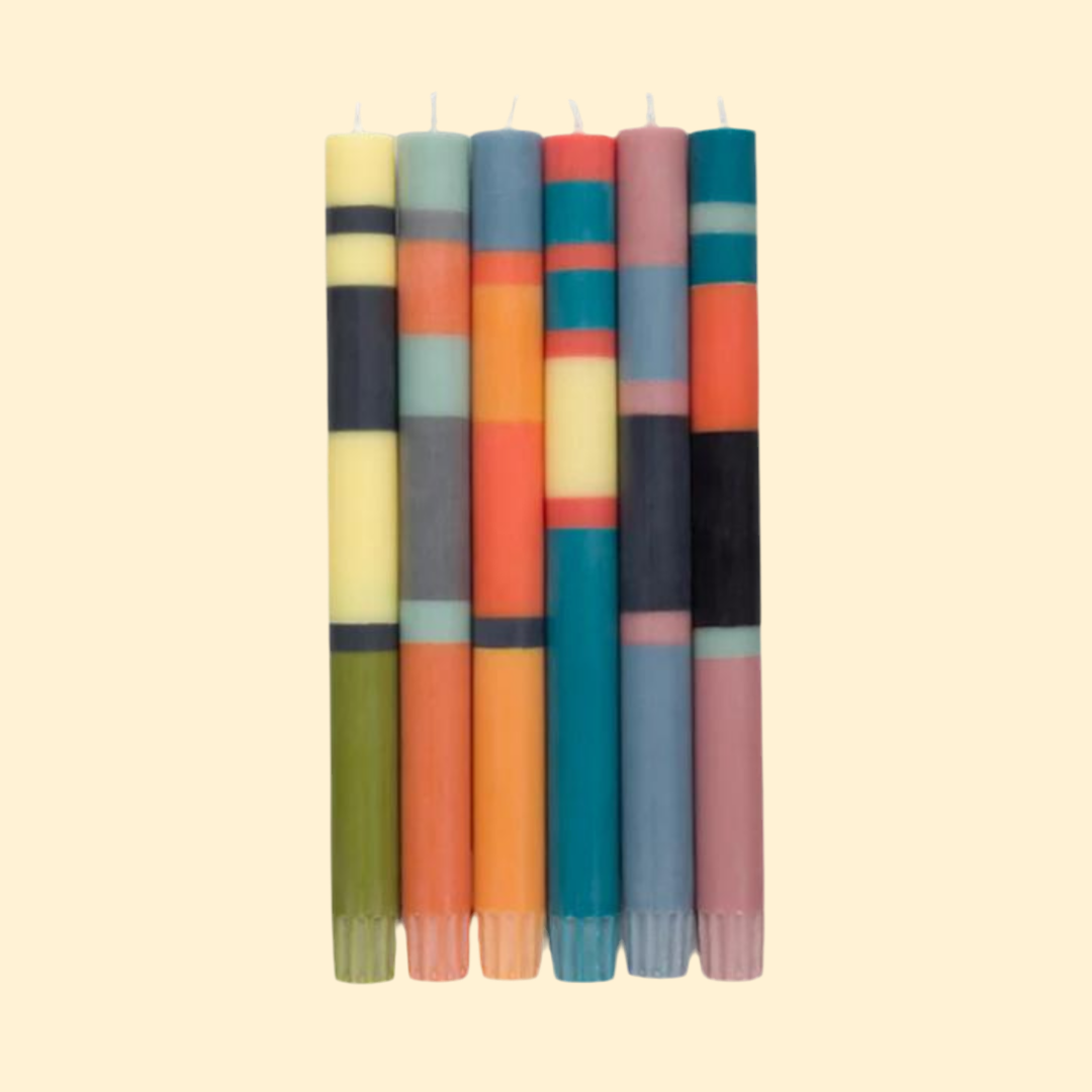 Six multicolored striped taper candles.  Each candle features horizontal bands of varying colors and widths.