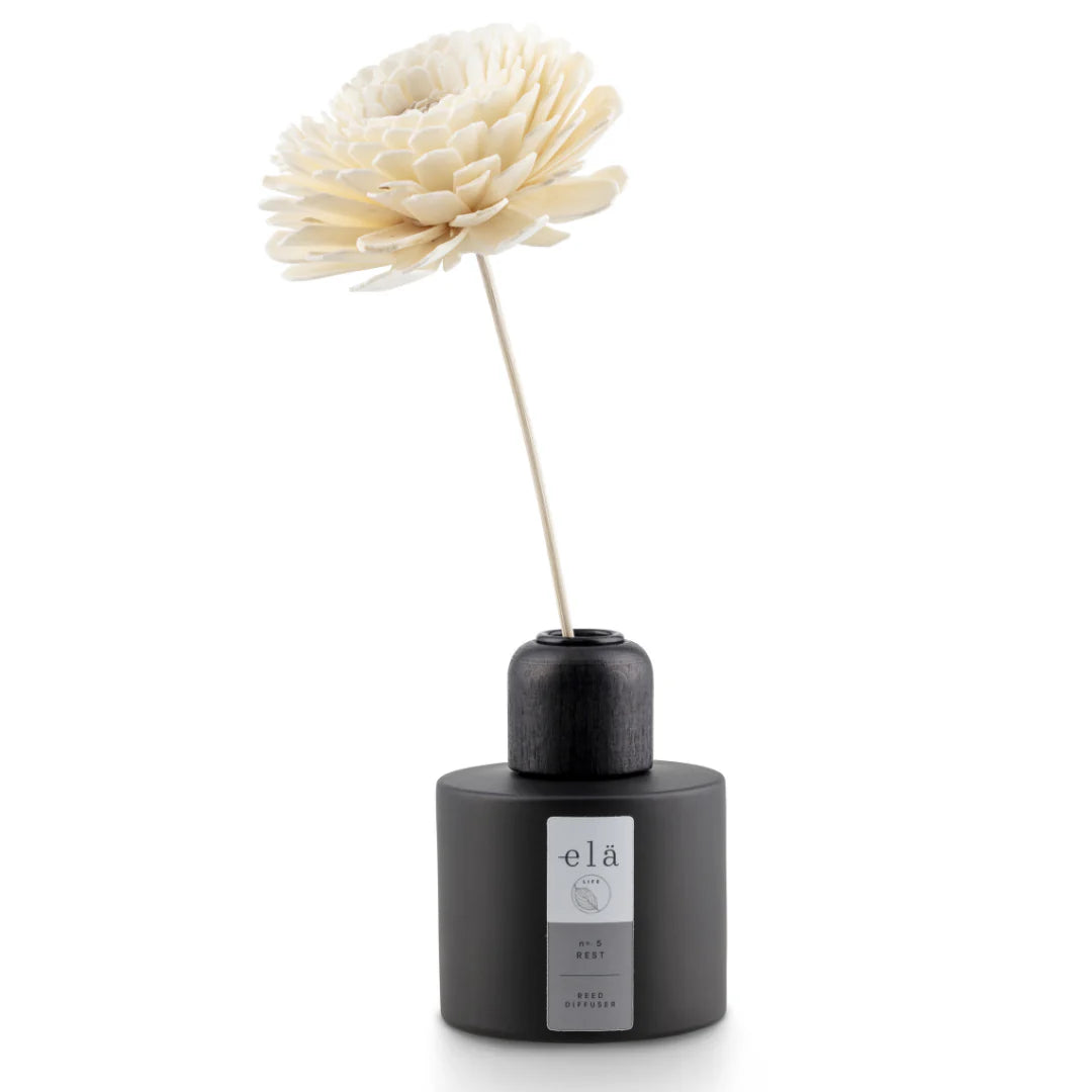 Black reed diffuser with a large, off-white sola flower diffuser stick.  The diffuser is labeled "elä" and "Rest."
