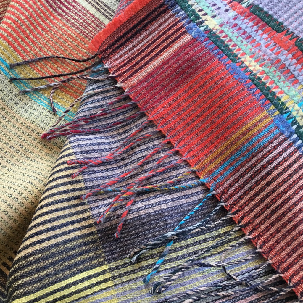 Multicolored striped woven scarf with fringed edges.