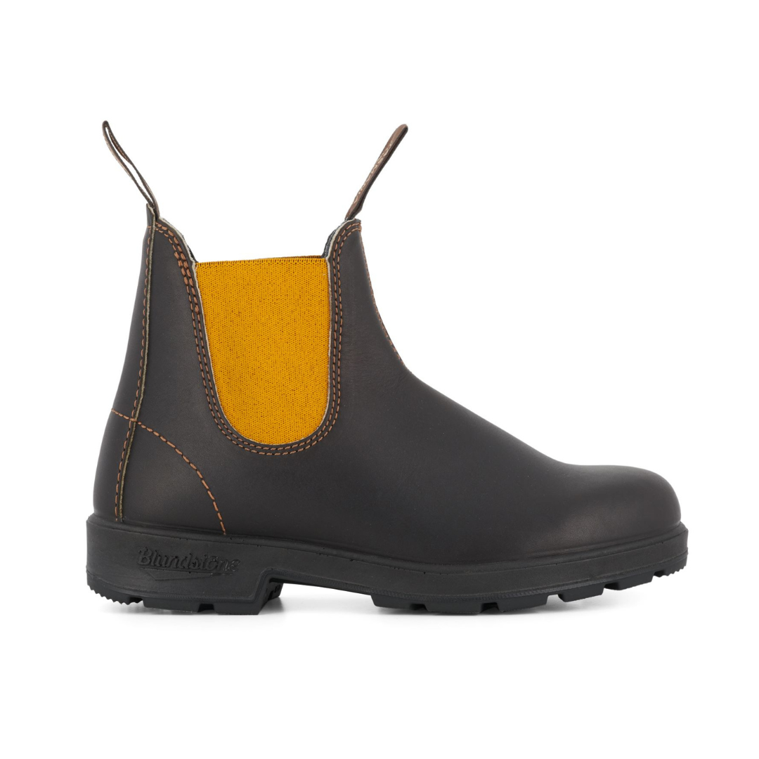 Black Blundstone Chelsea boot with a mustard yellow elastic side panel and a textured sole.