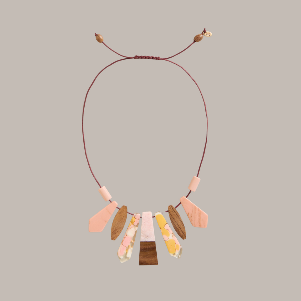 Statement necklace with maroon cord and assorted pink, peach, and brown resin and wood pendants.