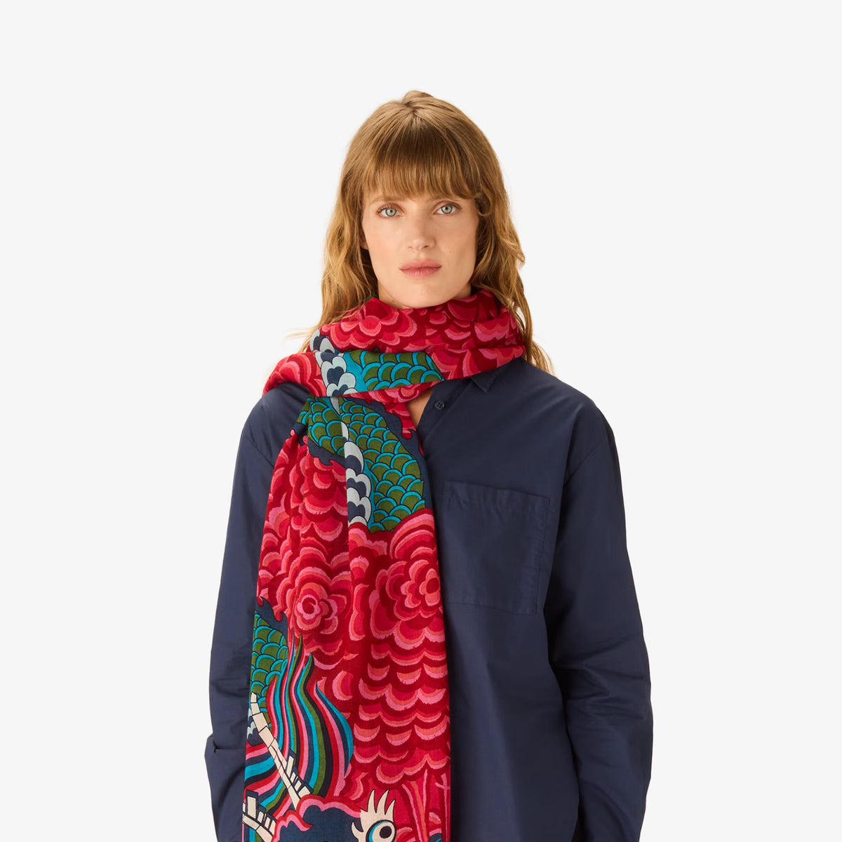 A model wearing a navy blue jacket and a vibrant red scarf with a detailed multicolor dragon pattern, set against a plain white background.