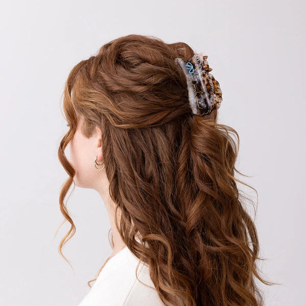 Woman with styled hair featuring a decorative hair clip on a white background
