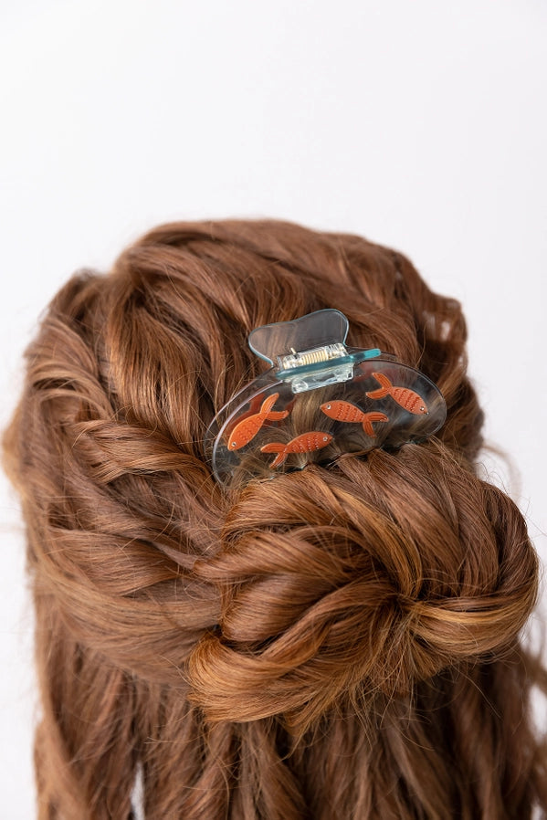 Hair clip with goldfish design in a braided hairstyle on a white background