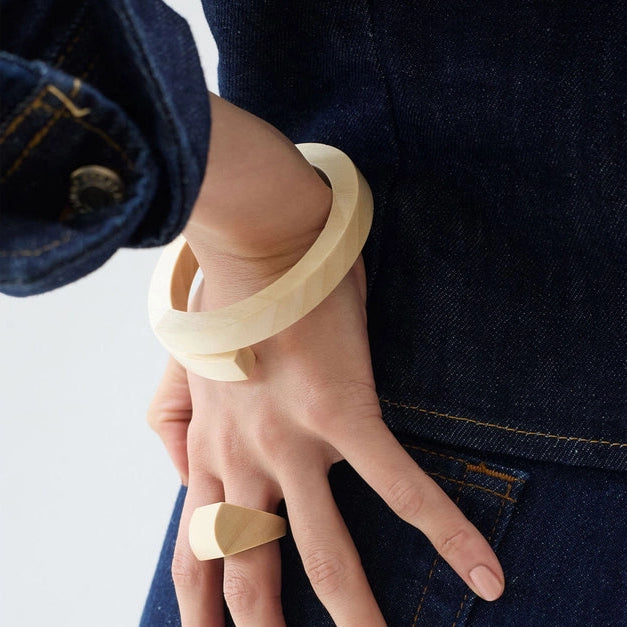 Person wearing two wooden bangles on a plain background