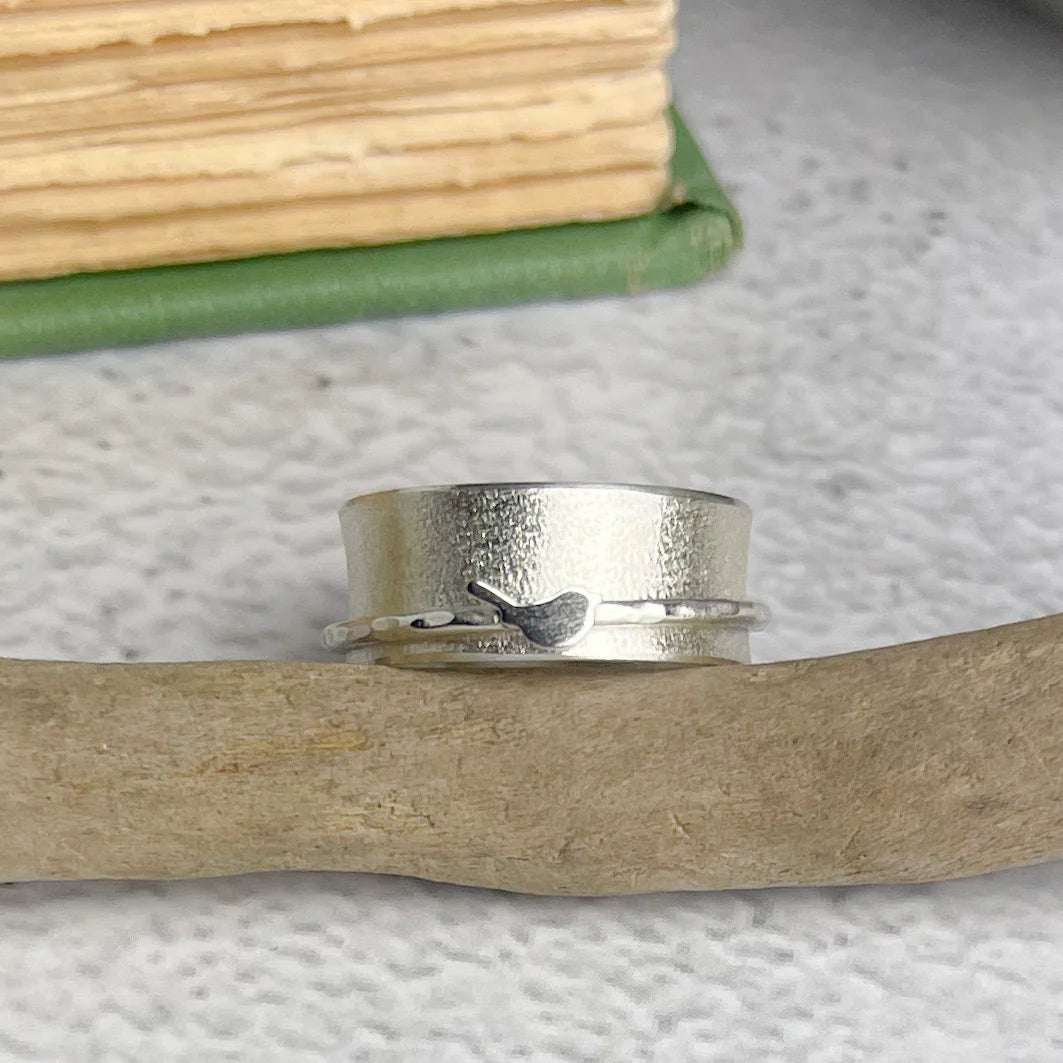 Silver spinner ring with textured band and small bird detail.