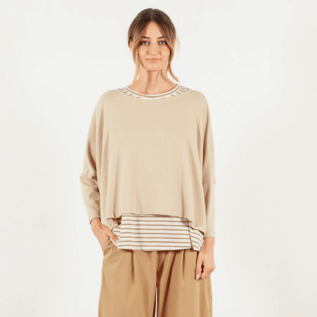 Woman wearing a beige sweater with striped details on a white background