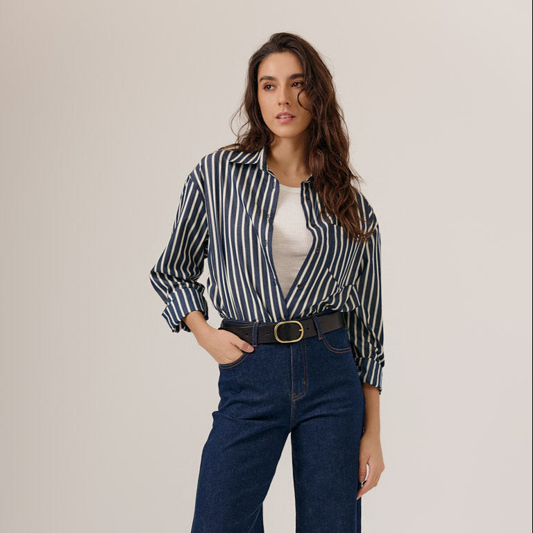 Woman wearing a striped shirt and jeans on a plain background