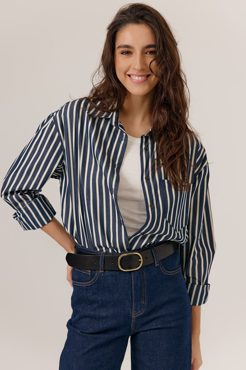 Woman wearing a striped shirt and jeans on a plain background