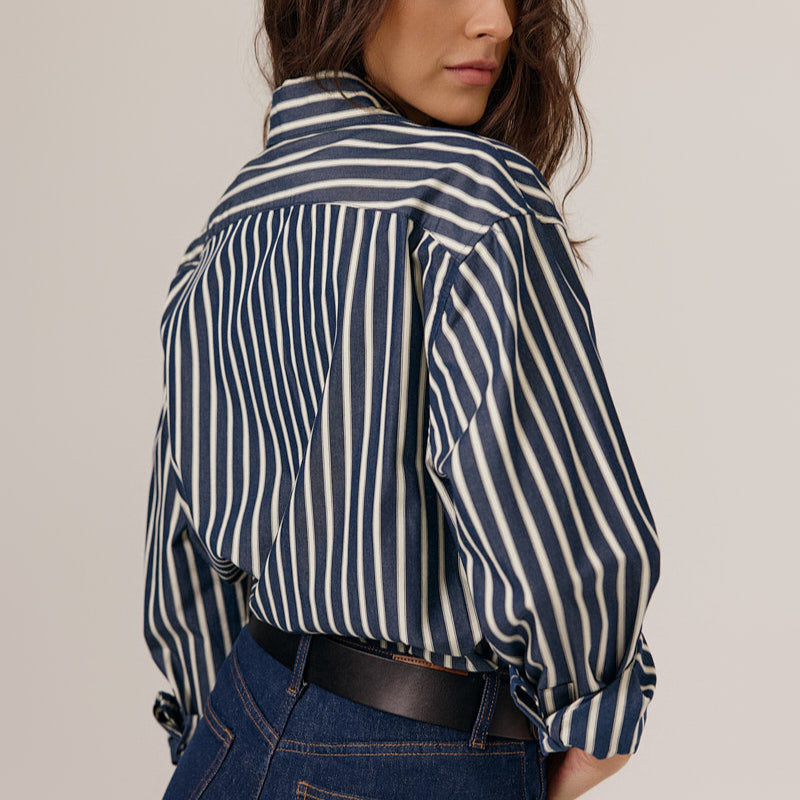 Person wearing a navy and white striped shirt with a plain background