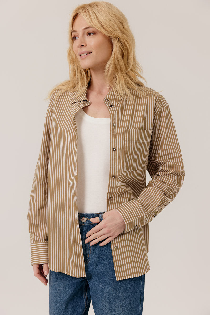 Woman wearing a beige striped shirt with a plain background