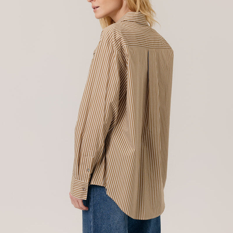Person wearing a beige and brown striped shirt with a plain background