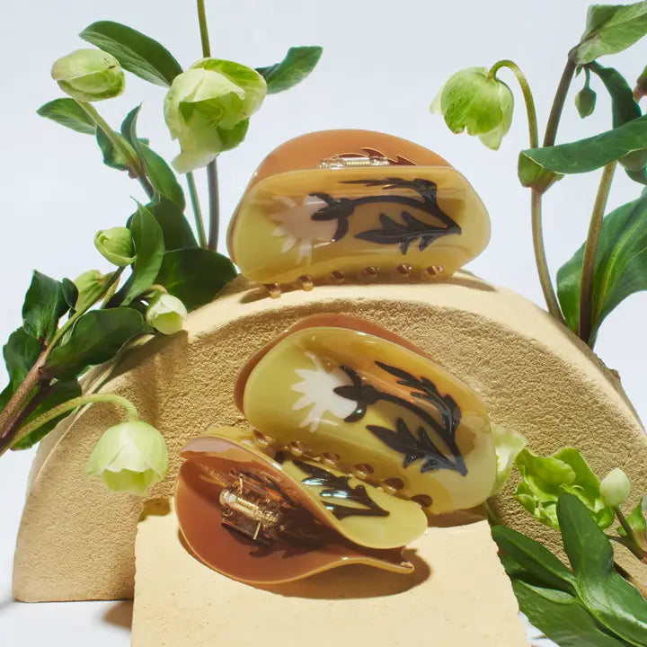 Decorative box with floral design on lid and base, surrounded by green leaves.