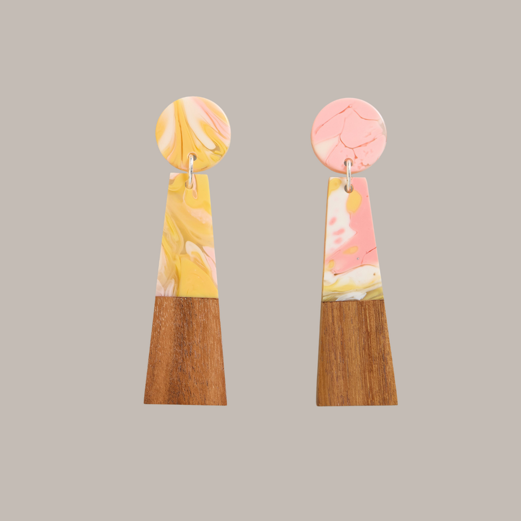 Pair of marbled resin and wood earrings. Yellow and pink resin tops with dark wood trapezoid bottoms.